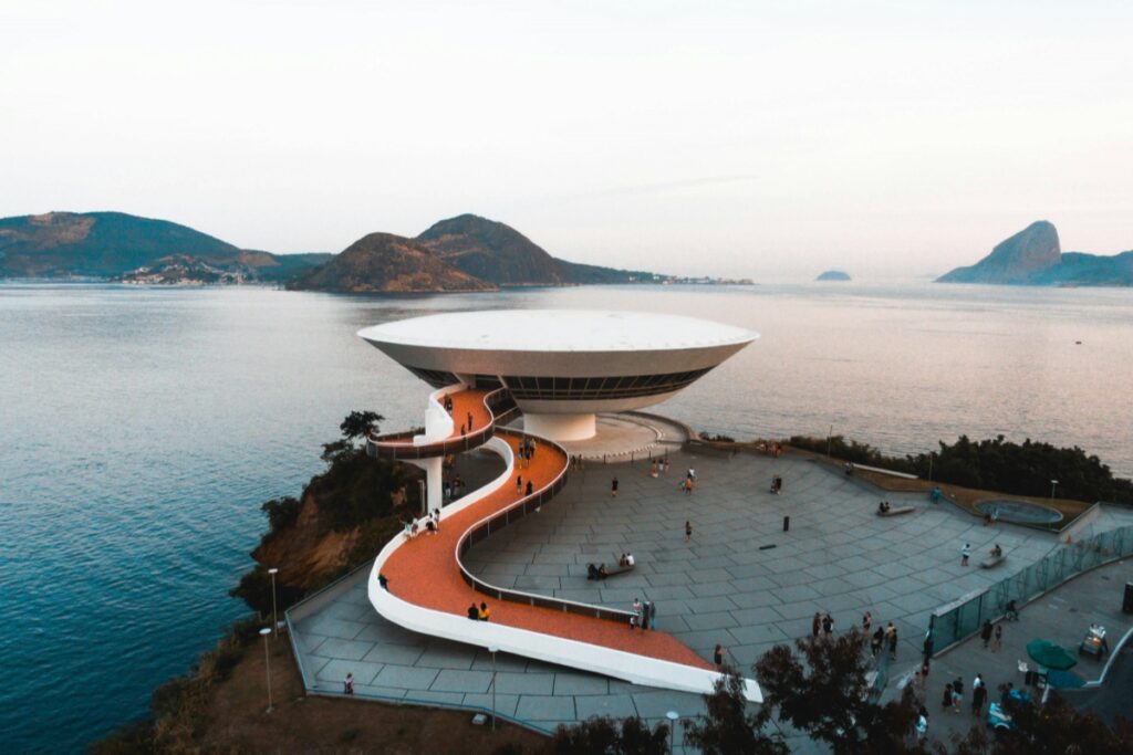 Esta imagem apresenta o icônico Museu de Arte Contemporânea do Rio de Janeiro (MAC), com sua estrutura futurista e arredondada, ressaltando sobre o mar. A escada serpenteante que conduz ao edifício é de um laranja vibrante, e pessoas podem ser vistas caminhando e apreciando o local. No fundo, as montanhas e a calma água do mar completam a paisagem. No contexto de "Pinterest Brasil O Poder do Marketing Visual para E-commerce", se você é um vendedor de produtos relacionados ao turismo, decoração ou até mesmo roupas com estilo moderno, imagens do MAC podem ser muito eficazes. Compartilhando - as no Pinterest e utilizando hashtags como #MACRio, #ArquiteturaBrasileira e #TurismoRio, você pode atrair o interesse de potenciais clientes, mostrando a beleza e a modernidade brasileira e, consequentemente, aumentar o tráfego e as vendas no seu e - commerce.