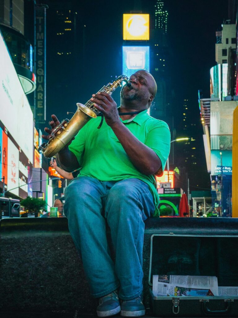 Imagem de um músico tocando saxofone sentado em um degrau, com o fundo iluminado pelas placa iluminadas de Times Square. Incluindo: Sobre o BaoLiba – Revolucionando o Marketing de Influência no Brasil